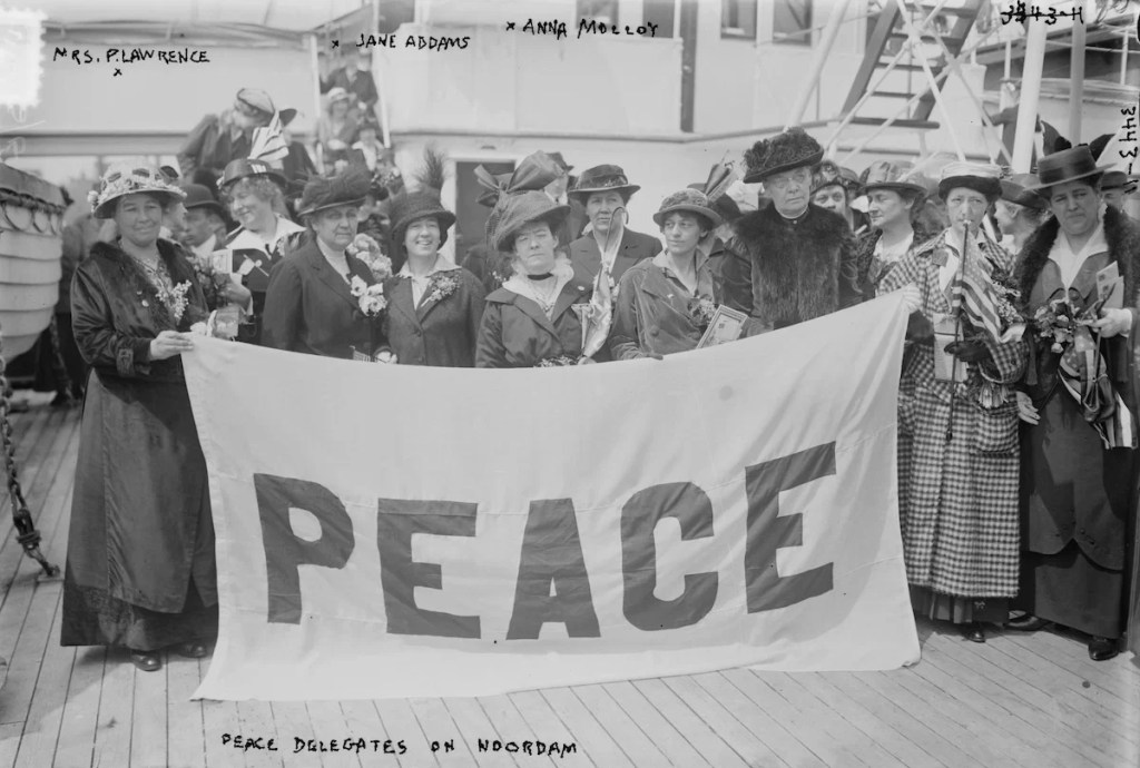 black and white image of protesting suffragettes holding a "peace" banner